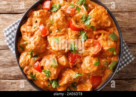 Poulet mafe africaine authentique dans la sauce d'arachide, avec des tomates, poivrons et lait de coco close-up dans une assiette sur la table. Vue supérieure horizontale de la société abo Banque D'Images