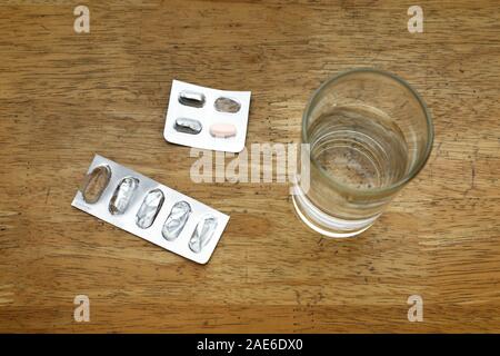 Photo de sachets médecine vide sur une table et le verre d'eau Banque D'Images