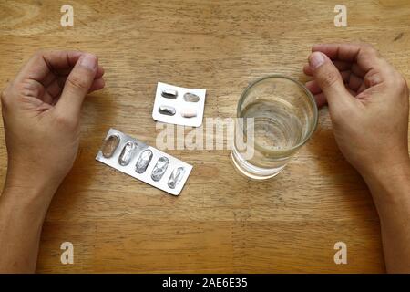 Photo de sachets médecine vide sur une table, un verre d'eau et paire de mains Banque D'Images