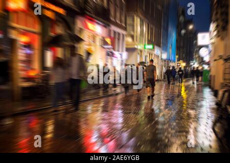 Motion floue image de personnes marchant sur la rue Warmoesstraat à Amsterdam. C'est l'une des principales rues commerçantes avec des cafés, restaurants et magasins. Banque D'Images