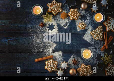 Biscuits au gingembre, épices et brûler des bougies sur une étoile de sucre glace sur un fond de bois bleu foncé comme une mise à plat de Noël avec copie espace, h Banque D'Images