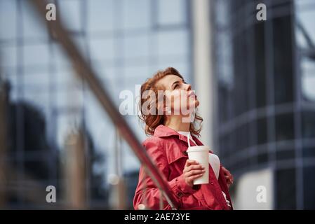 En attendant le beau temps. Hot woman in red coat ont chaud à pied dans la ville à son temps le week-end Banque D'Images