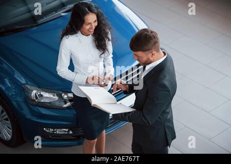 Jeune fille sourit. La clientèle féminine et moderne et son homme barbu dans le salon de l'automobile Banque D'Images