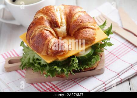 Des petits croissants sandwich pour petit déjeuner rapide avec le fromage cheddar, le concombre, et la laitue. Servi sur la petite planche à découper en bois avec fourchette et k Banque D'Images