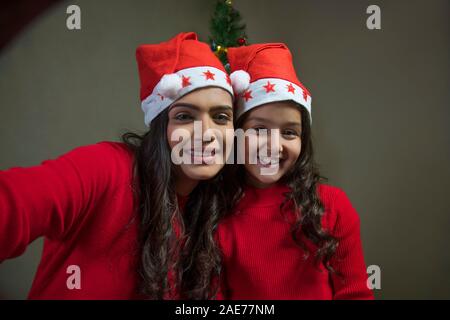 Mère et fille making faces en cliquant autoportraits ensemble. (Noël) Banque D'Images