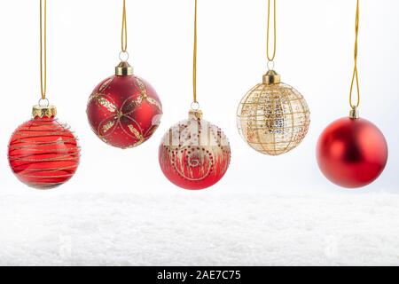 Ensemble de cinq belles boules rouges et or de Noël blanc sur fond de neige. Joyeux Noël et Bonne Année concept. Banque D'Images