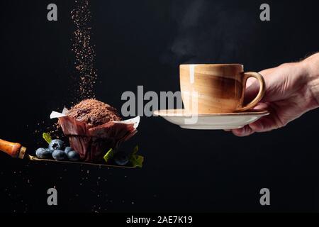 Muffin au chocolat avec des bleuets et menthe saupoudré de miettes de chocolat. Muffin et brown tasse avec du café chaud ou un thé. Copier l'espace. Banque D'Images