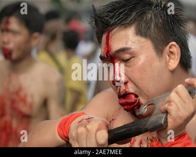 Dévot Taoïste Chinois Thaï coupe son front et de la langue avec une hache tranchant pendant le Festival Végétarien de Phuket (neuf dieux Empereur Festival). Banque D'Images