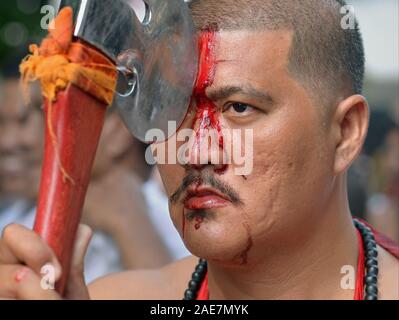 Dévot Taoïste Chinois Thaï coupe son front avec une hache pendant le Festival Végétarien de Phuket (neuf dieux Empereur Festival). Banque D'Images