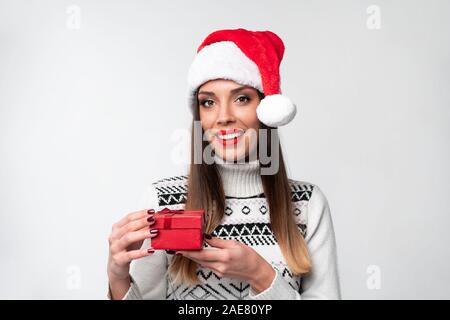 Beautifiul Close up portrait of young woman in red Santa hat on white background studio. Nouveau concept de vacances de Noël année surpris fille mignonne dents Banque D'Images