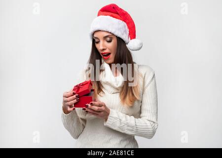 Beautifiul Close up portrait of young woman in red Santa hat on white background studio. Nouveau concept de vacances de Noël année surpris fille mignonne smili Banque D'Images
