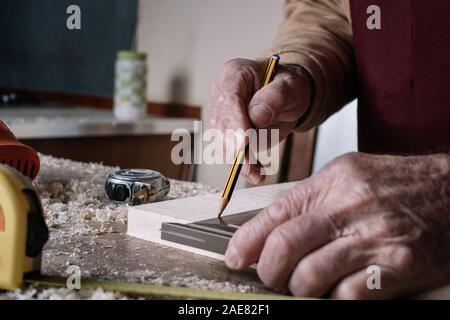 Carpenter la prise de mesures sur une table avec un crayon et un carré en métal Banque D'Images