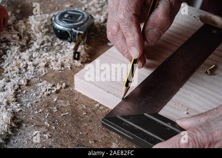 Carpenter la prise de mesures sur une table avec un crayon et un carré en métal Banque D'Images