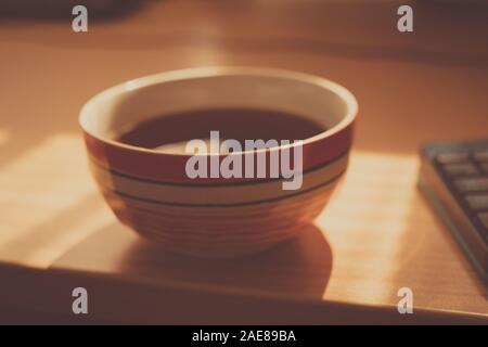 Grande cuvette ronde avec plateau noir verre sur sunny brown table. Banque D'Images