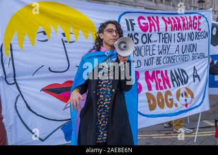 Londres, Royaume-Uni. 7 décembre 2019. Un Allemand transgenre résidant au Royaume-Uni parle lors de la 'bum Boys contre Boris' rassemblement à Downing St., Boris Johnson, a déclaré : "Si le mariage gay était OK puis j'ai vu aucune raison de principe pour laquelle un syndicat ne devrait pas être consacré entre trois hommes et un chien." les militants LGBT + qui ont repris l'étiquette de Boris 'bum boys' organiser un mariage pour 3 hommes et un chien à l'extérieur de l'administration centrale de la campagne des Conservateurs pour protester contre cette et ses autres homophobe, raciste, sexiste et ableist commentaires avant de marcher à un rassemblement à l'extérieur de Downing St Peter Marshall/Alamy Live News Banque D'Images