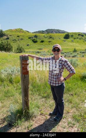 Femme se tient fièrement à côté du marqueur sur Sentier randonnée des prairies Banque D'Images