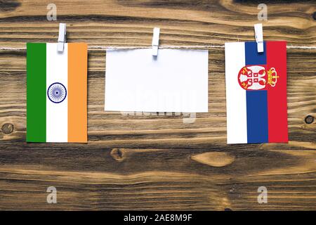 Drapeaux suspendus de l'Inde et la Serbie attaché à corde avec pinces à linge avec de l'espace de copie sur papier blanc sur fond de bois.Les relations diplomatiques bet Banque D'Images
