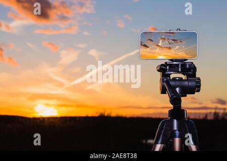 En utilisant comme smartphone appareil photo professionnel sur trépied pour la capture de l'image superbe coucher du soleil Banque D'Images