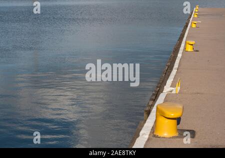 L'eau du port et une partie de la requête avec bollards jaune pour les bateaux comme arrière-plan with copy space Banque D'Images