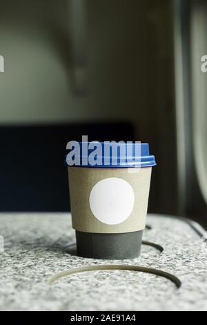 Une tasse de café en papier avec un couvercle en plastique bleu et un cercle inscription blanche Banque D'Images