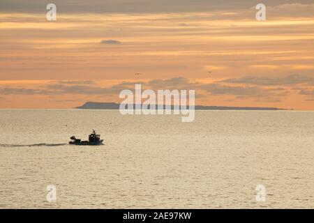 Un bateau de pêche côtière qui a quitté le port à Lyme Regis de partir à l'aube d'un matin glacial au début de décembre 2019. L'île de Banque D'Images