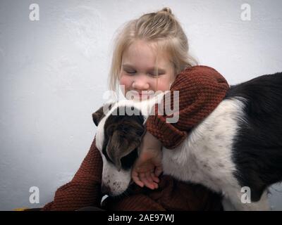 Baby Girl hugs son chien préféré. Un jeune chiot Banque D'Images