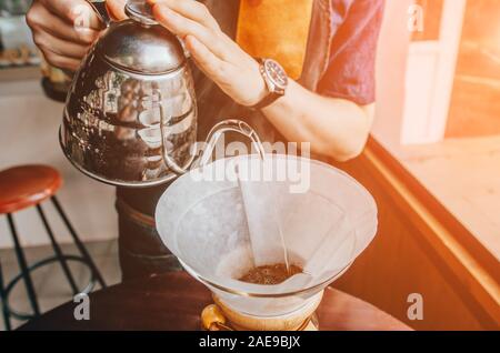 La préparation du café barista filtre extérieur. Jeune homme barista pouring eau bouillante d'électrique Banque D'Images