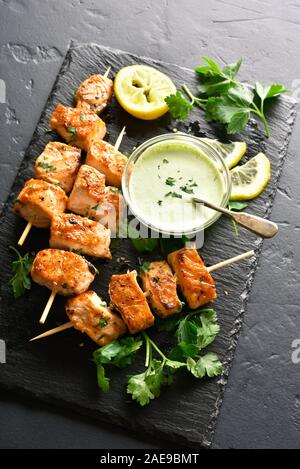 Brochette de saumon grillé. Brochettes de saumon sur ardoise sur fond noir en noir. Banque D'Images