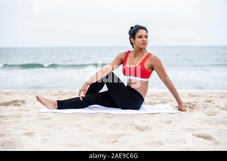 Extension des jambes Femme effectue sur la plage Banque D'Images