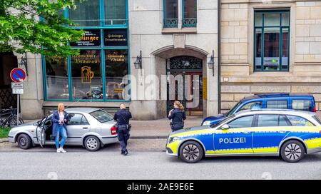 Les policiers et les policiers arrêtent un conducteur féminin pour une infraction à la circulation à Altstadt Hambourg, Allemagne. Banque D'Images