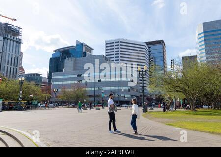 Portland, Oregon / USA - Circa 2019 : un jeune homme et une femme ayant une conversation au bord de l'eau fontaine en centre-ville de Portland, Oregon. Banque D'Images