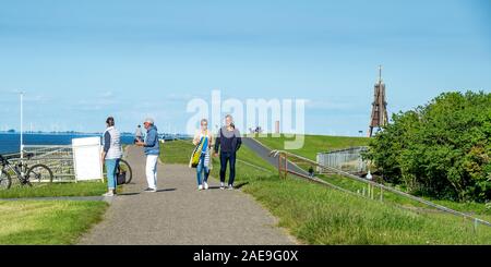 Marcheurs et cyclistes récréatifs sur un sentier de vélo le long d'une digue et Kugelbake Beacon point de repère nautique à Cuxhaven Basse-Saxe Allemagne. Banque D'Images