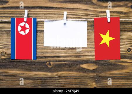 Drapeaux suspendus de la Corée du Nord et le Vietnam attaché à corde avec pinces à linge avec de l'espace de copie sur papier blanc sur fond de bois.e diplomatique Banque D'Images