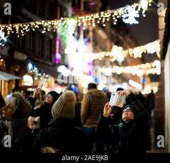 Strasbourg, France - Dec 20, 2016 : rue française avec un grand groupe de personnes woman taking photograph sur le smartphone de l'animation de rue du Maroquin décoré bokeh pour Marché de Noël illuminations Banque D'Images