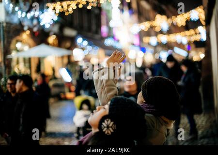 Strasbourg, France - Dec 20, 2016 : rue française avec un grand groupe de personnes woman taking photograph sur le smartphone de l'animation de rue du Maroquin décoré bokeh pour Marché de Noël illuminations Banque D'Images