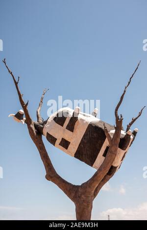 Melbourne, Australie - 16 novembre 2009 : Vache noir et blanc à l'arrière situé au sommet de l'arbre est marron sculpture contre le ciel bleu. Banque D'Images