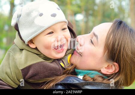 Heureuse mère et bébé rire dans le parc Banque D'Images