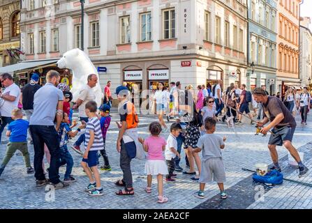 Homme faisant des bulles et des enfants tentant de capturer les bulles et le costume d'ours polaire dans la vieille ville de Prague, République tchèque. Banque D'Images