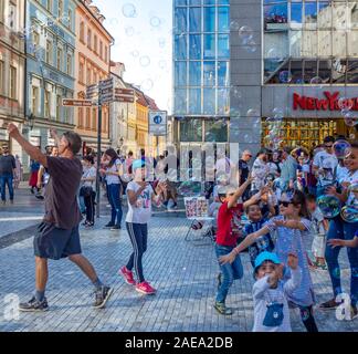 L'homme qui fait des bulles et des enfants qui tentent de capturer les bulles dans la vieille ville de Prague, République tchèque. Banque D'Images