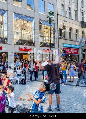 L'homme qui fait des bulles et des enfants qui tentent de capturer les bulles dans la vieille ville de Prague, République tchèque. Banque D'Images