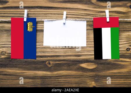 Drapeaux suspendus du Liechtenstein et Emirats Arabes Unis attaché à la corde avec des pinces à linge avec de l'espace de copie sur papier blanc sur fond de bois.Di Banque D'Images