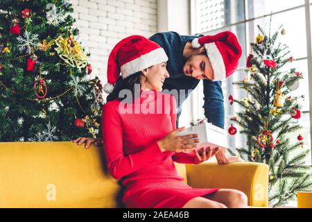Doux romantique en couple santa hats s'amusant decorating Christmas Tree et souriant tout en célébrant l'nouvel an et profiter de passer du temps togethe Banque D'Images