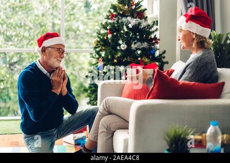 Doux romantique couple santa hats s'amusant et souriant tout en célébrant l'nouvel an et profiter de passer du temps ensemble.Senior man giving Banque D'Images