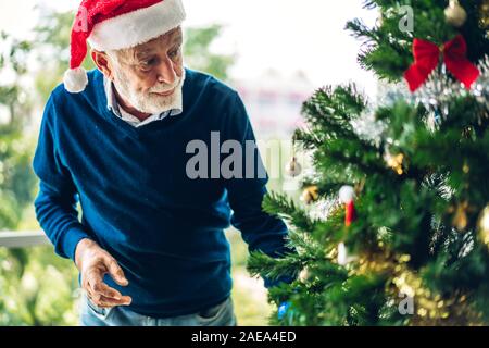 Senior woman relaxing near christmas tree et souriant tout en célébrant l'nouvel an et profiter de passer du temps ensemble dans le temps de Noël à l'hom Banque D'Images