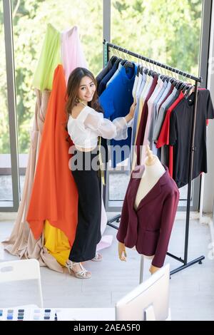 Vue de dessus du créateur de mode des jeunes adultes debout près de rack de vêtements et à la mode avec des vêtements faits main élégante à son atelier comme s Banque D'Images