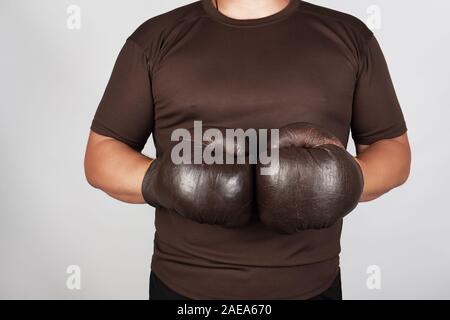 L'homme se tient en tenue très old vintage brown des gants de boxe sur ses mains, fond blanc Banque D'Images