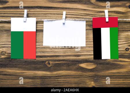 Drapeaux suspendus de Madagascar et des Emirats Arabes Unis attaché à la corde avec des pinces à linge avec de l'espace de copie sur papier blanc sur fond de bois.Diplo Banque D'Images