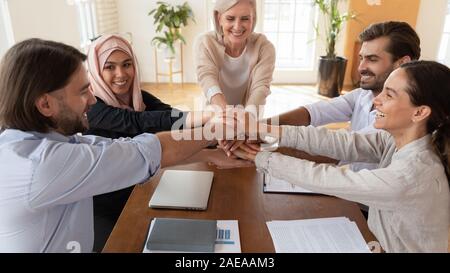 Heureux les jeunes et d'âge moyen de l'équipe multiraciale mettant les mains ensemble. Banque D'Images