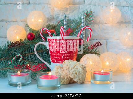 Une tasse de lait avec des bonbons et biscuits de Noël à la noix de coco sur l'arrière-plan des décorations de Noël. Banque D'Images