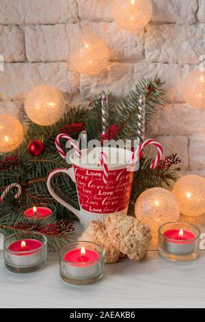 Une tasse de lait avec des bonbons et biscuits de Noël à la noix de coco sur l'arrière-plan des décorations de Noël. Banque D'Images